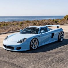 a blue sports car parked in front of the ocean