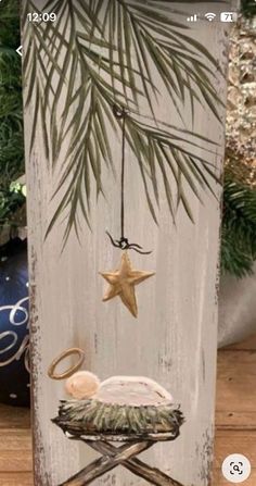 a wooden sign with a star hanging from it's side and a nativity scene in the middle