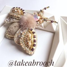 the brooch is adorned with pearls and beads, as well as a tassel