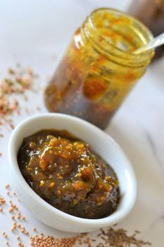 a small white bowl filled with food next to a jar full of mustard and seasoning