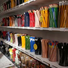 there are many different colored pencils on the shelves in this store, all lined up