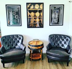 two black leather chairs sitting next to each other in front of pictures on the wall