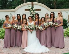 a group of women standing next to each other in front of a wall with flowers