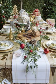 the table is set for christmas dinner with plates, silverware and other holiday decorations