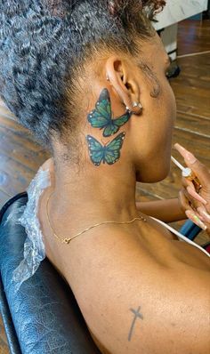 a woman with a butterfly tattoo on her upper back neck and behind her ear, sitting in a chair