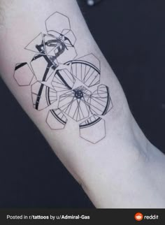 a black and white photo of a wheel tattoo on the left inner arm with an arrow in it