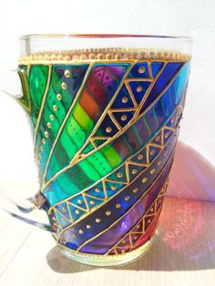 a colorful glass cup sitting on top of a wooden table