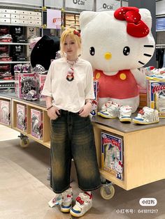 a girl standing in front of a hello kitty stuffed animal