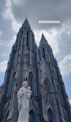 a large cathedral with a statue in front of it's entrance and cloudy sky