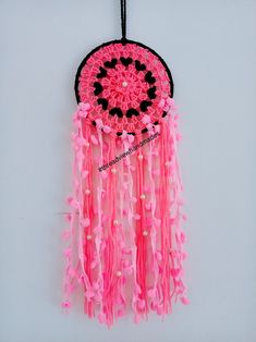 a pink and black dream catcher hanging on a wall