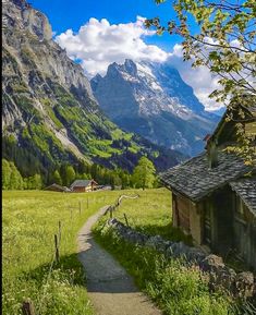 an old house in the mountains with a path leading to it