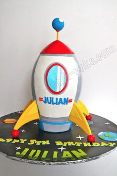 a cake shaped like a rocket ship on top of a black plate with the name julian written on it