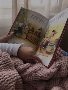 a child is reading a book on the bed