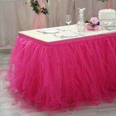 there is a table with a pink tulle skirt on it and two white plates