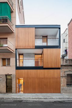 an apartment building with wooden panels and balconies on the outside, along side a street