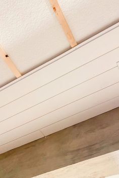 an air vent in the ceiling with some wood planks on it and a white painted wall