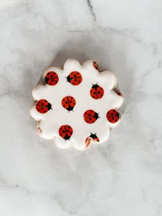 a white plate with red and black ladybugs on it sitting on a marble surface