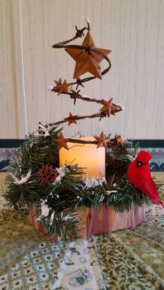 a christmas tree made out of branches and candles on a table with a red bird sitting in the center