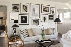 a living room filled with white furniture and pictures on the wall above it's coffee table