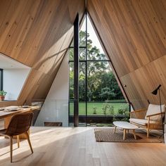 a room with wooden walls and flooring that has windows on both sides, looking out onto a grassy field