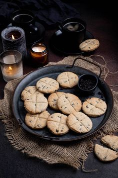 chocolate chip cookies on a black plate next to candles