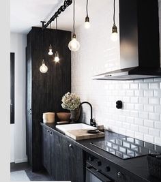 a black and white kitchen with lights hanging from the ceiling