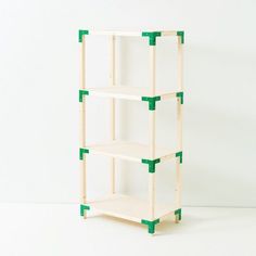 a three tiered shelf with green pegs on the top and bottom shelves, against a white wall