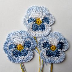 three crocheted blue and white flowers with yellow centers