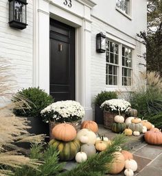 a house with white flowers and pumpkins in the front yard, on instagram