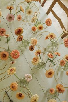 several vases filled with flowers sitting on top of a wooden table next to chairs