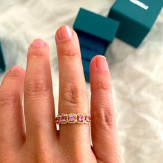 a woman's hand with a pink and white diamond ring on top of it