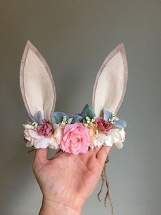 a hand holding up a flower crown with bunny ears on it