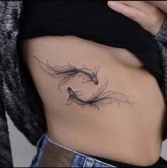 a woman's stomach with two fish tattoos on her belly and the bottom part of her lower back