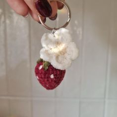 a hand holding a keychain with a strawberries and cream flower on it