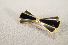 I am offering this fabulous vintage yellow gold tone pin. This piece is truly gorgeous, and it has the following features: * beautiful vintage brooch * enameled * jet black * bow design * 2 inch in length This is a fantastic and classic piece. There is tons of sparkle and shine with this piece. It will beautifully complement your upcoming fashion season. Buyer pays all shipping and handling. Black Brooch Lapel Pin As Gift, Black Lapel Pin Brooch For Gift, Black Lapel Pin Brooch As Gift, Vintage Black Pins For Gifts, Vintage Black Pins As Gifts, Vintage Black Pins For Gift, Vintage Black Pins As Gift, Vintage Black Brooch Lapel Pin, Vintage Black Enamel Pin For Gift