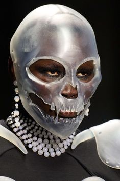 a woman with white makeup and skeleton make - up on her face, wearing silver jewelry