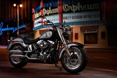 a motorcycle is parked on the side of the road at night in front of a theater