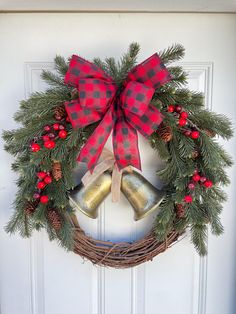 a christmas wreath with two bells hanging from it