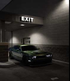 a green car is parked in front of an exit sign at the entrance to a building