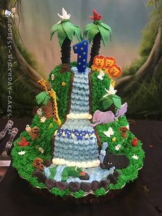 a cake made to look like a waterfall with animals and trees on the top is sitting on a table