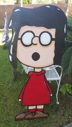 a cardboard cutout of a cartoon character with glasses and a red dress standing in the grass