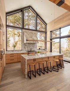 a large kitchen with an island counter top and wooden cabinets in front of windows that look out onto the woods