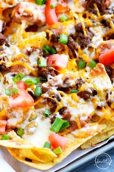 the nachos are loaded with meat, cheese and vegetables on top of them