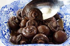 a blue and white bowl filled with chocolate covered doughnuts next to a spoon