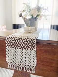 a crocheted table runner sitting on top of a wooden table