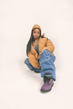 a doll is sitting on the ground wearing jeans and a jacket with hoodie over it