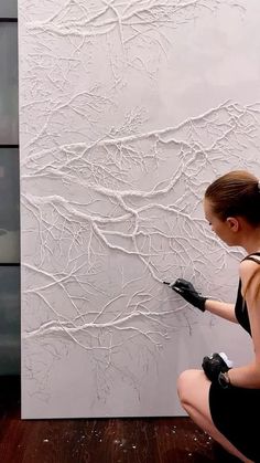 a woman in black gloves painting a wall with white paint on the walls and wood flooring