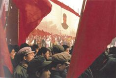 a group of people holding red flags in front of a crowd