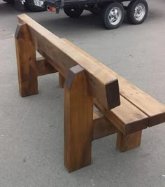 a wooden bench sitting in the middle of a parking lot next to a large truck