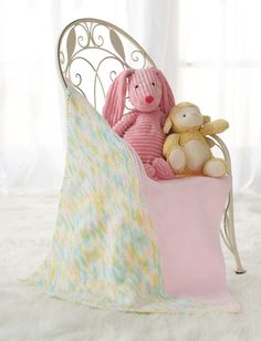 two stuffed animals are sitting in a bed with white sheets and blankets on top of it